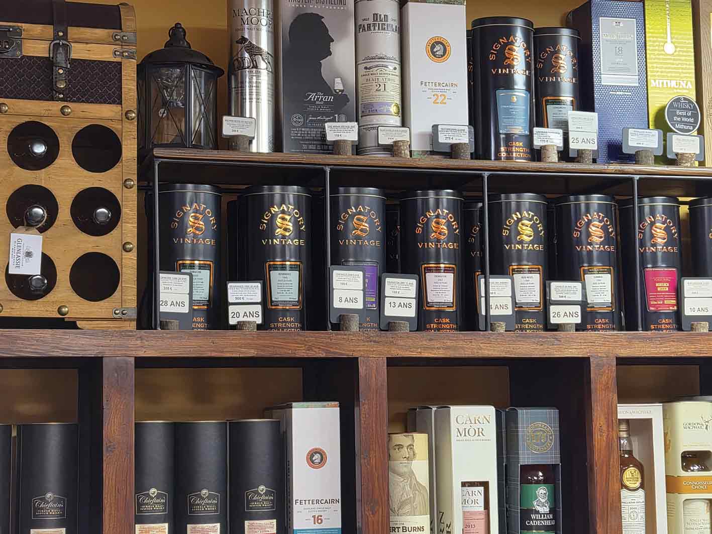 Whiskies rares : pourquoi certaines bouteilles deviennent-elles si recherchées ? 6 Une collection impressionnante de whiskies rares et exclusifs, mettant en vedette des bouteilles Signatory Vintage, Fettercairn et Carn Mòr sur des étagères en bois.